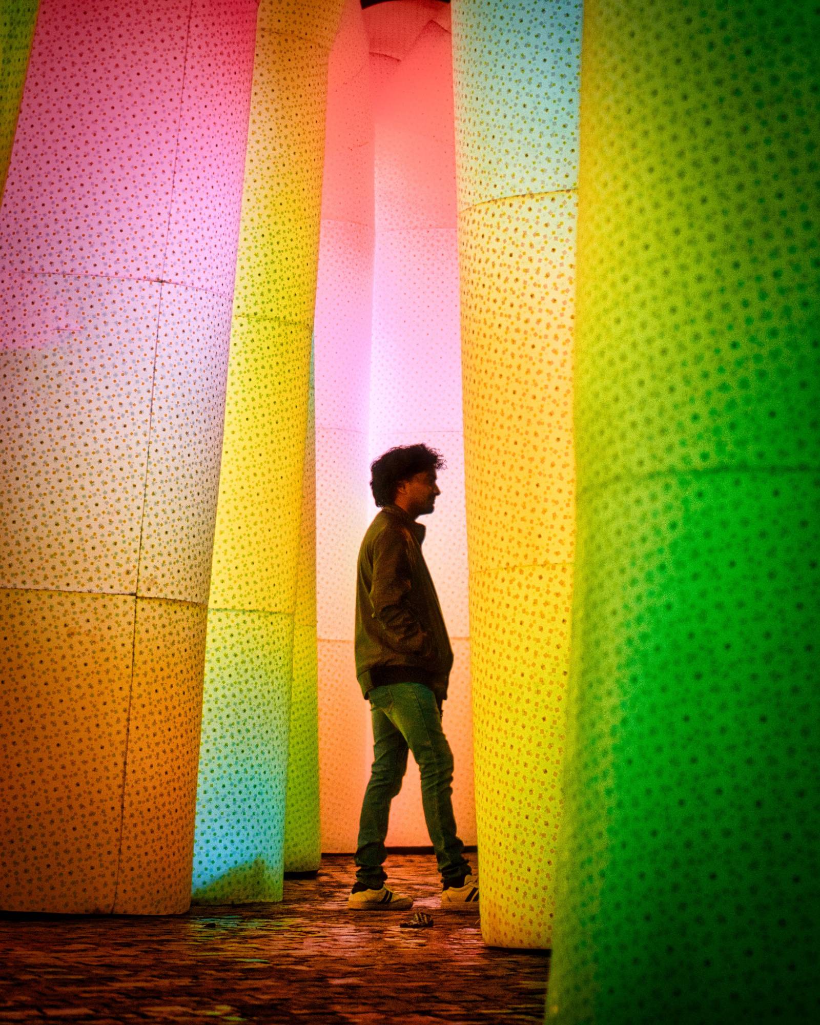 A figure silhouetted between rows of colourful illuminated columns